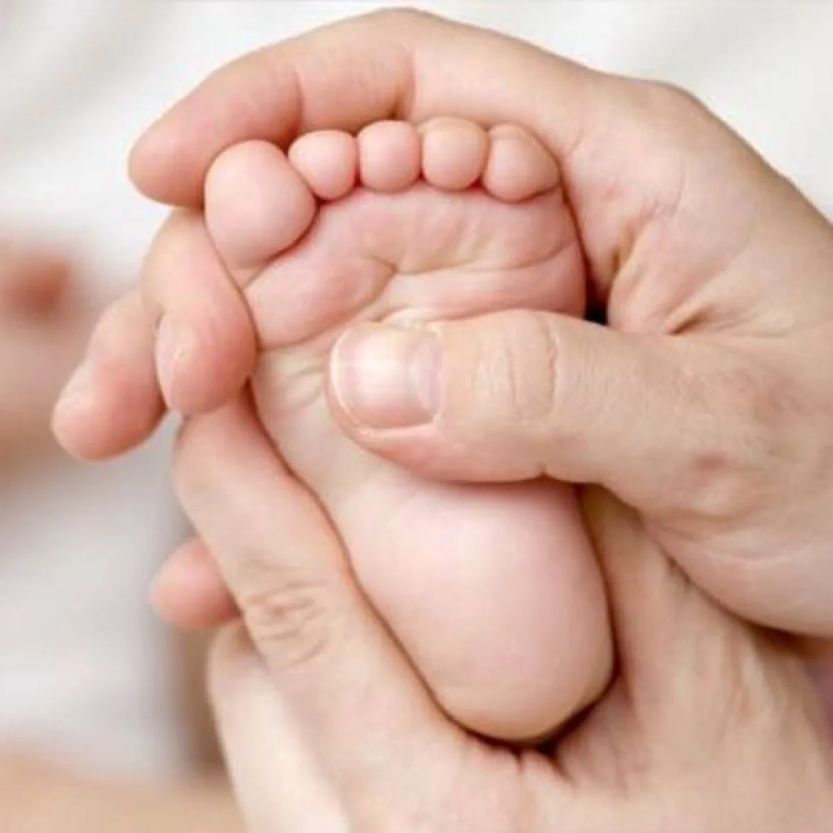 Rustige babymassage: handen masseren zachtjes het voetje van een baby
