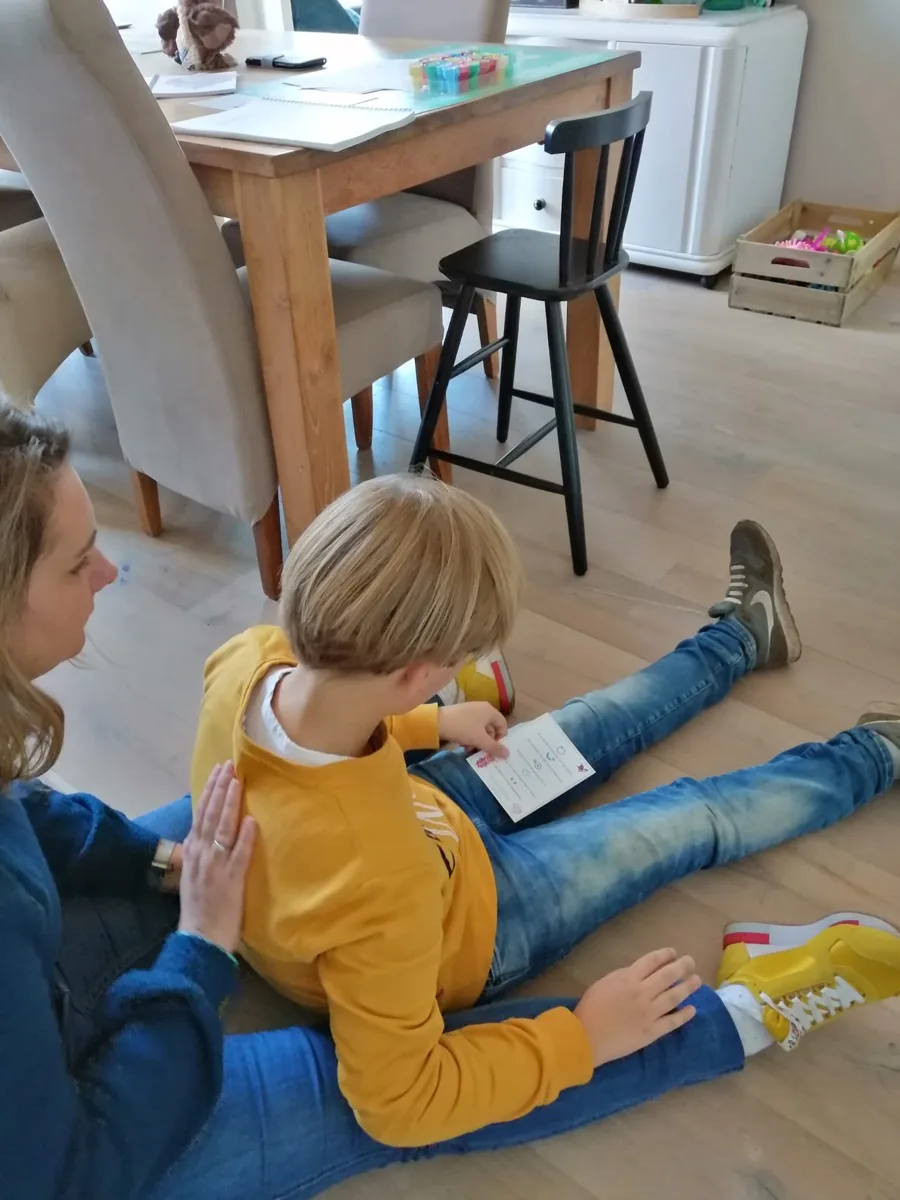 Kindermassage: moeder masseert de rug van haar zoontje aan de hand van een kaartje